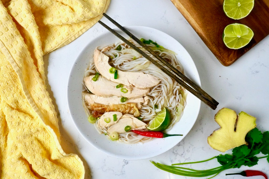 Delicious looking bowl of noodles, broth and chicken slices with lime, chili and cilantro - Chicken Pho - Pho Ga